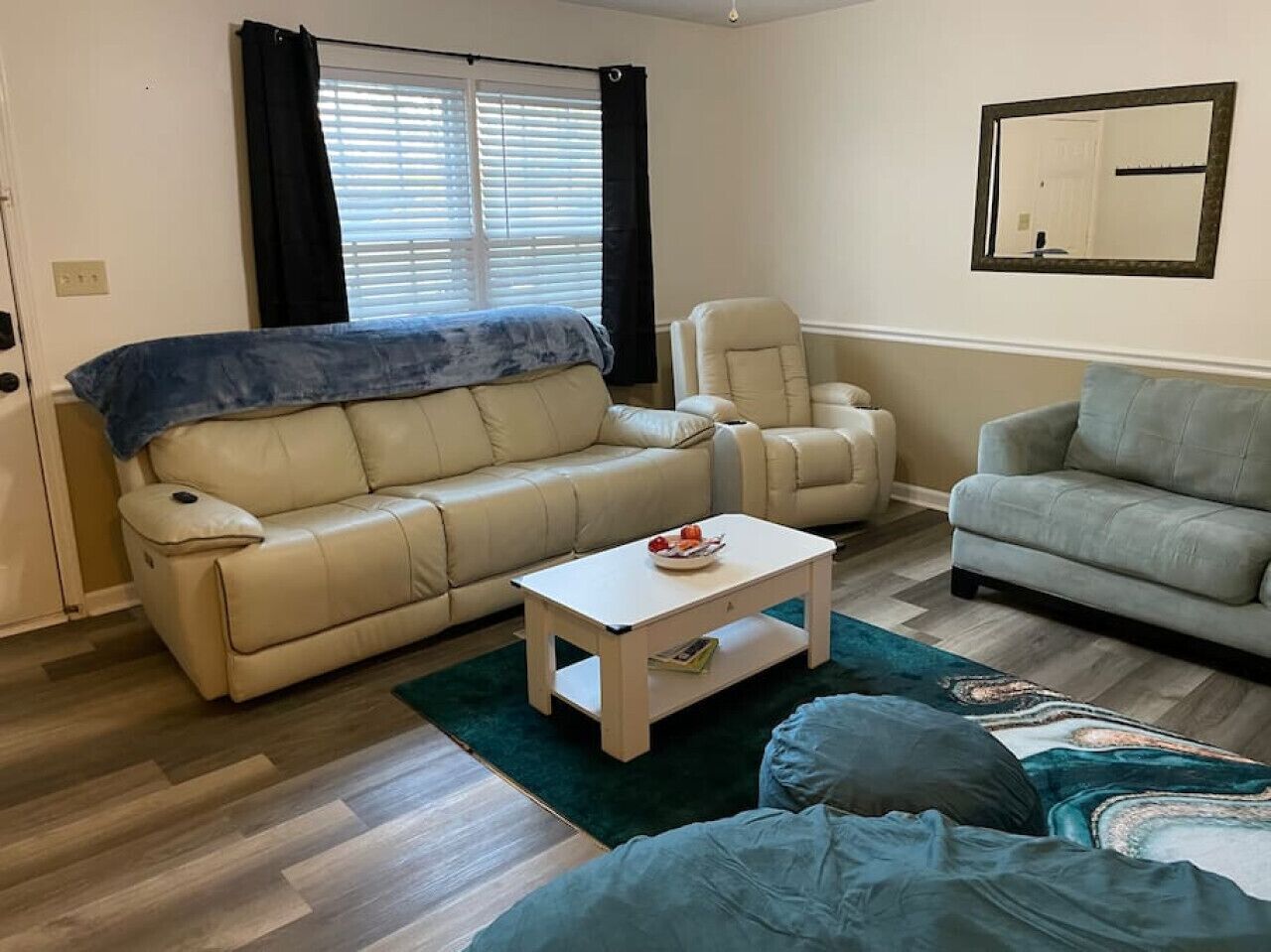 A living room with a beige sofa, a grey sofa, a white coffee table, and a patterned rug.