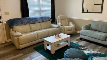 A living room with a beige sofa, a grey sofa, a white coffee table, and a patterned rug.