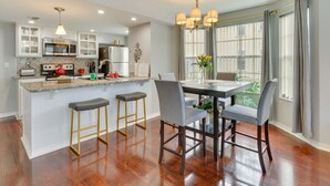 A modern kitchen with white cabinets, a granite countertop, and a central island with bar stools. - Kissimmee Condo w/ Perks: 6 Mi to Disney World! (Kissimmee)