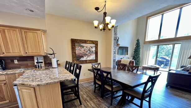A spacious kitchen with wooden cabinets, a granite countertop, and a dining area with a large table and chairs.