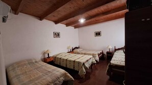 Ein Zimmer mit drei Betten, Holzbalkendecke und zwei gerahmten Bildern an den Wänden.