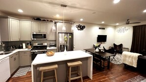 A modern kitchen with white cabinets, stainless steel appliances, and a central island with stools.