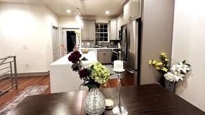 A modern kitchen with stainless steel appliances, a white island, and a dining area with a dark wood table.