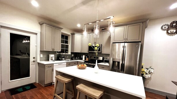 A modern kitchen with white cabinets, stainless steel appliances, and a central island with stools.