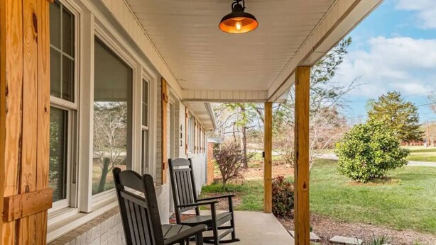 A covered porch with two wooden chairs and a hanging light fixture. - Spacious 3BD 2BA w/fenced yard & direct bike trail access. Near GVL, TR, Furman. (Greenville)