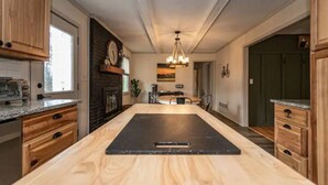 A modern kitchen with wooden cabinets, a central island, a built-in stove, and a dining area with chairs. - Spacious 3BD 2BA w/fenced yard & direct bike trail access. Near GVL, TR, Furman. (Greenville)
