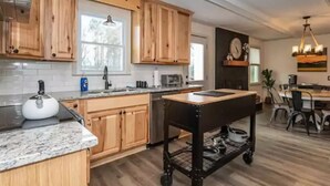 A modern kitchen with wooden cabinets, a granite countertop, a kettle, and a cart. - Spacious 3BD 2BA w/fenced yard & direct bike trail access. Near GVL, TR, Furman. (Greenville)