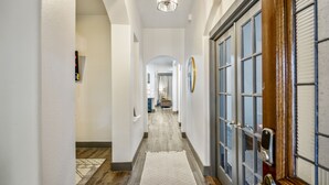 A hallway with a wooden floor, a patterned rug, and a door with glass panels.