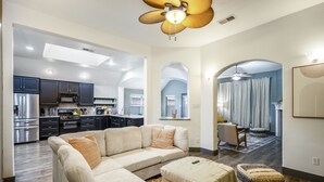 A modern living room with a sectional sofa, ottoman, and a ceiling fan.