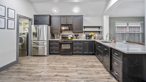 A modern kitchen with dark cabinets, stainless steel appliances, and a large island.