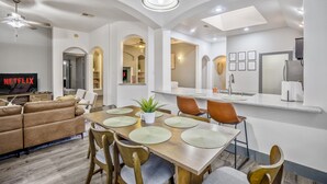 A modern living room with a TV, sofa, and dining area with a table and chairs.