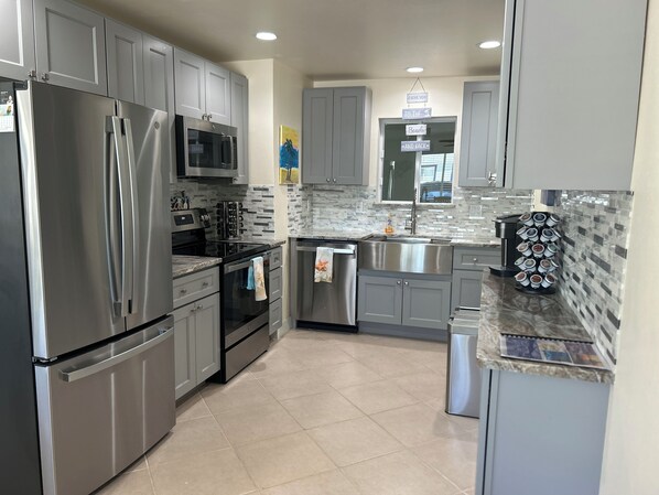 A modern kitchen with stainless steel appliances, grey cabinets, and a tiled backsplash.