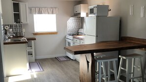 A compact kitchen with a wooden island, white appliances, and a window providing natural light. - Sweet Escape Cottage on River  (Barton)