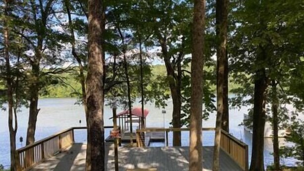 Une jetée en bois s’étendant dans un lac, entourée d’arbres.