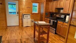 L’intérieur d’une cabane en bois comprend un coin cuisine équipé de placards, d’un four à micro-ondes, d’un four et d’une petite table.