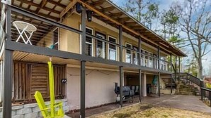 Ein zweistöckiges Haus mit überdachter Veranda, einem Basketballkorb und einem Grill.