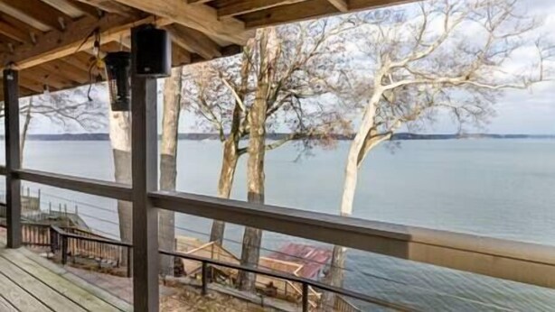 Eine überdachte Terrasse mit Blick auf einen See und Bäume.