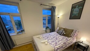 Une chambre à coucher avec un lit, une table de chevet, une lampe et une fenêtre.