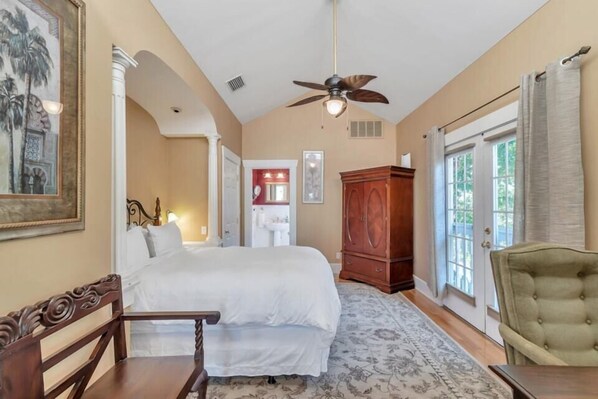 Une chambre à coucher avec un lit, une chaise en bois, une grande armoire et un ventilateur de plafond.