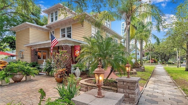 A two-story house with a brick facade, a front porch, and a flag. - Walnut Room at ONE Inn, Comfy, Steps to Downtown St. Pete: Ideal for all guests! (Saint Petersburg)