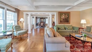 A spacious living room with a wooden floor, a green sofa, a beige sofa, and a dining area in the background. - Walnut Room at ONE Inn, Comfy, Steps to Downtown St. Pete: Ideal for all guests! (Saint Petersburg)
