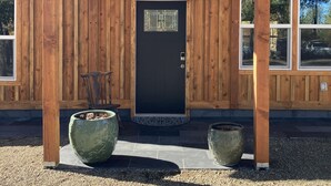 A wooden building with a black door, a hanging light fixture, and two large planters. - Abundant Activities for Adventurous People (Goldendale)