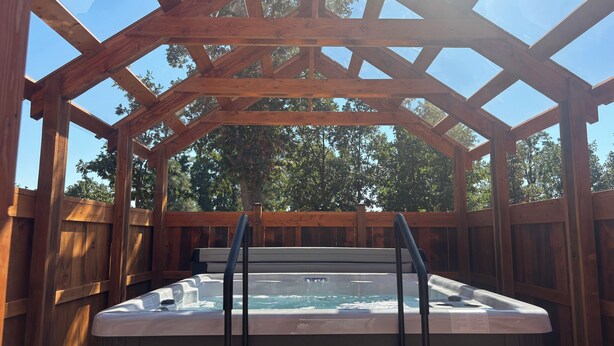 A hot tub under a wooden pergola with a view of trees. - Abundant Activities for Adventurous People (Goldendale)