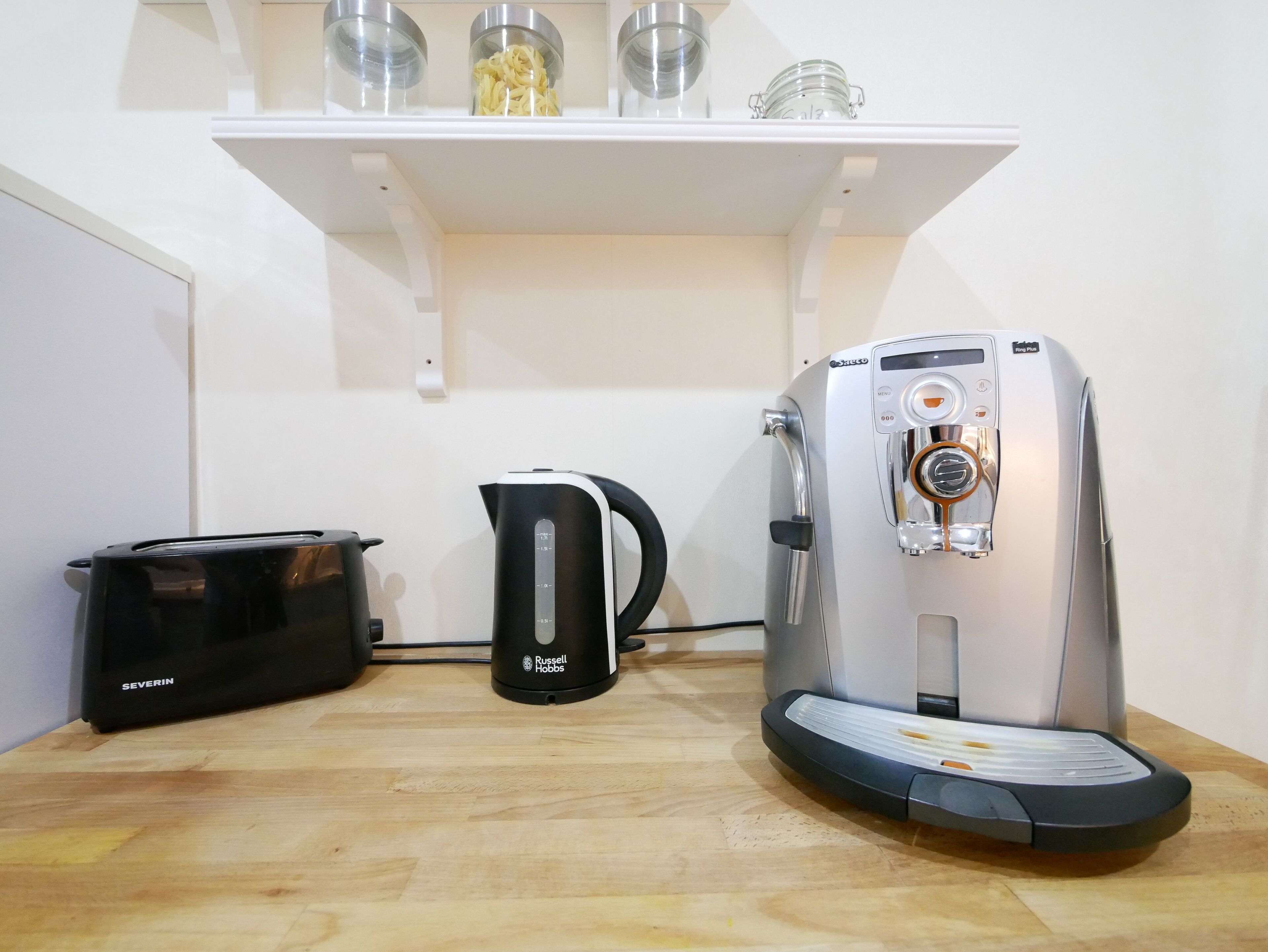 Une cuisine équipée d’une machine à café, d’une bouilloire et d’un autocuiseur sur le plan de travail.
