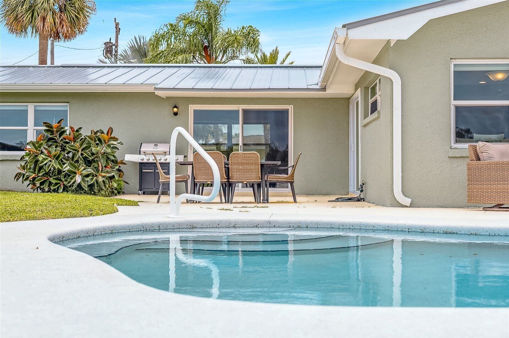 Un espace piscine résidentiel comprenant une terrasse, du mobilier d’extérieur et un barbecue.