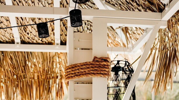 Un espace aménagé au bord de la piscine, avec une pergola blanche, un panier en osier et un saladier en bois rempli de fruits.