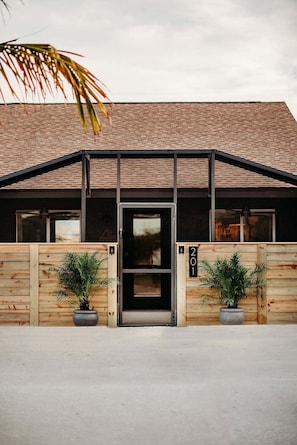 A building with a brick roof, a black-framed entrance, and wooden walls.