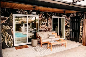 A modern living area with a sofa, coffee table, and a glass door leading to a pool.