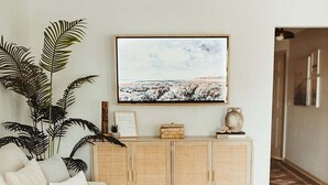 Un salon comprenant un canapé, une table basse, un téléviseur et un meuble.
