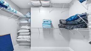 A neatly organized laundry room with shelves for folded clothes, a drying rack, and a blue mat on the floor. - 8023 Magnolia Ave (Cape Canaveral)