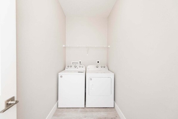 A laundry room with two white washers and dryers, a white ceiling, and a light switch on the wall. - 313 Surf Drive (Cape Canaveral)
