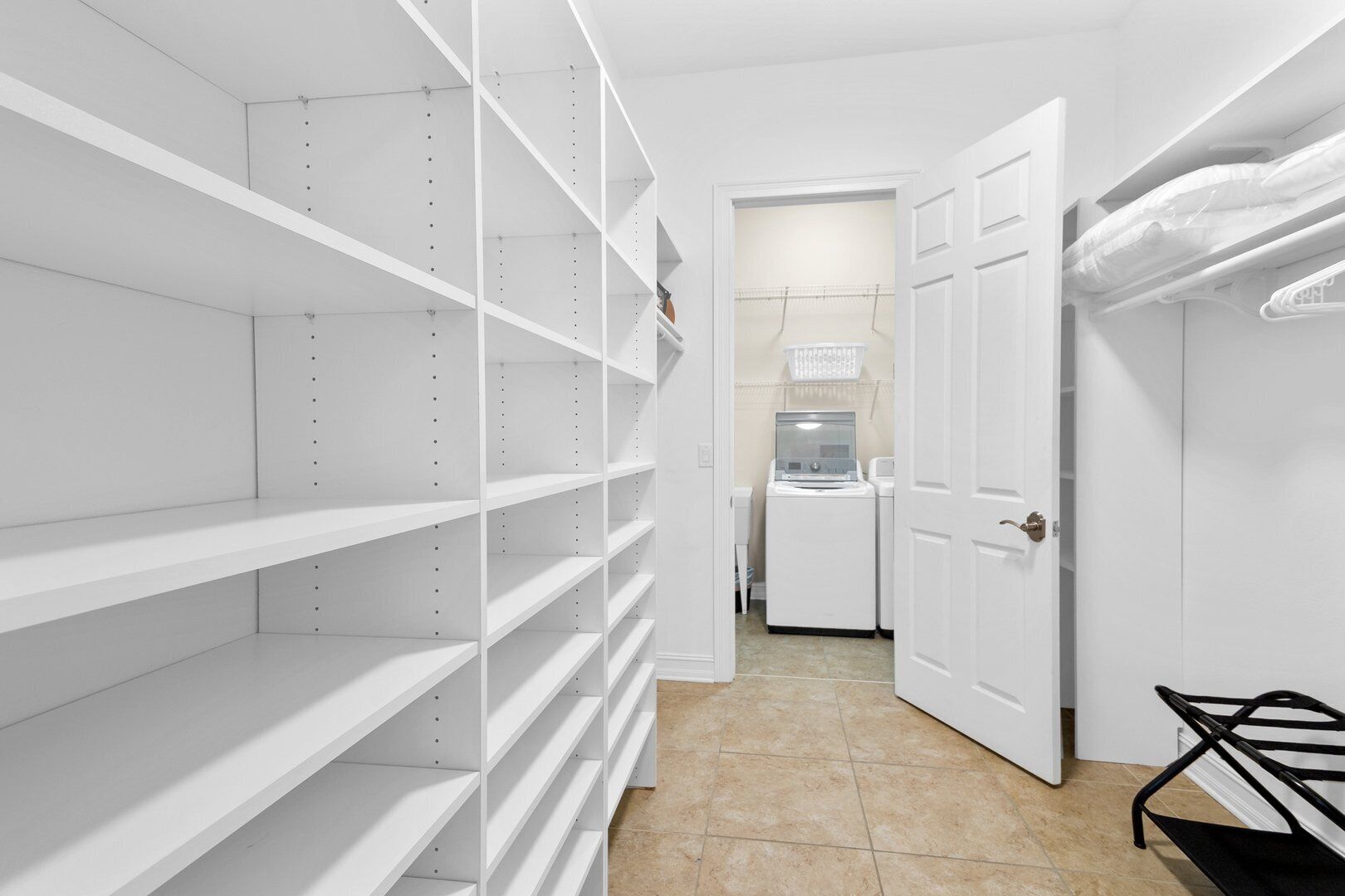 A laundry room with white shelves, a washing machine, and a dryer.