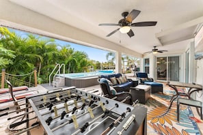 Un patio al aire libre con piscina, zona de estar y mesa de fútbol de mesa.
