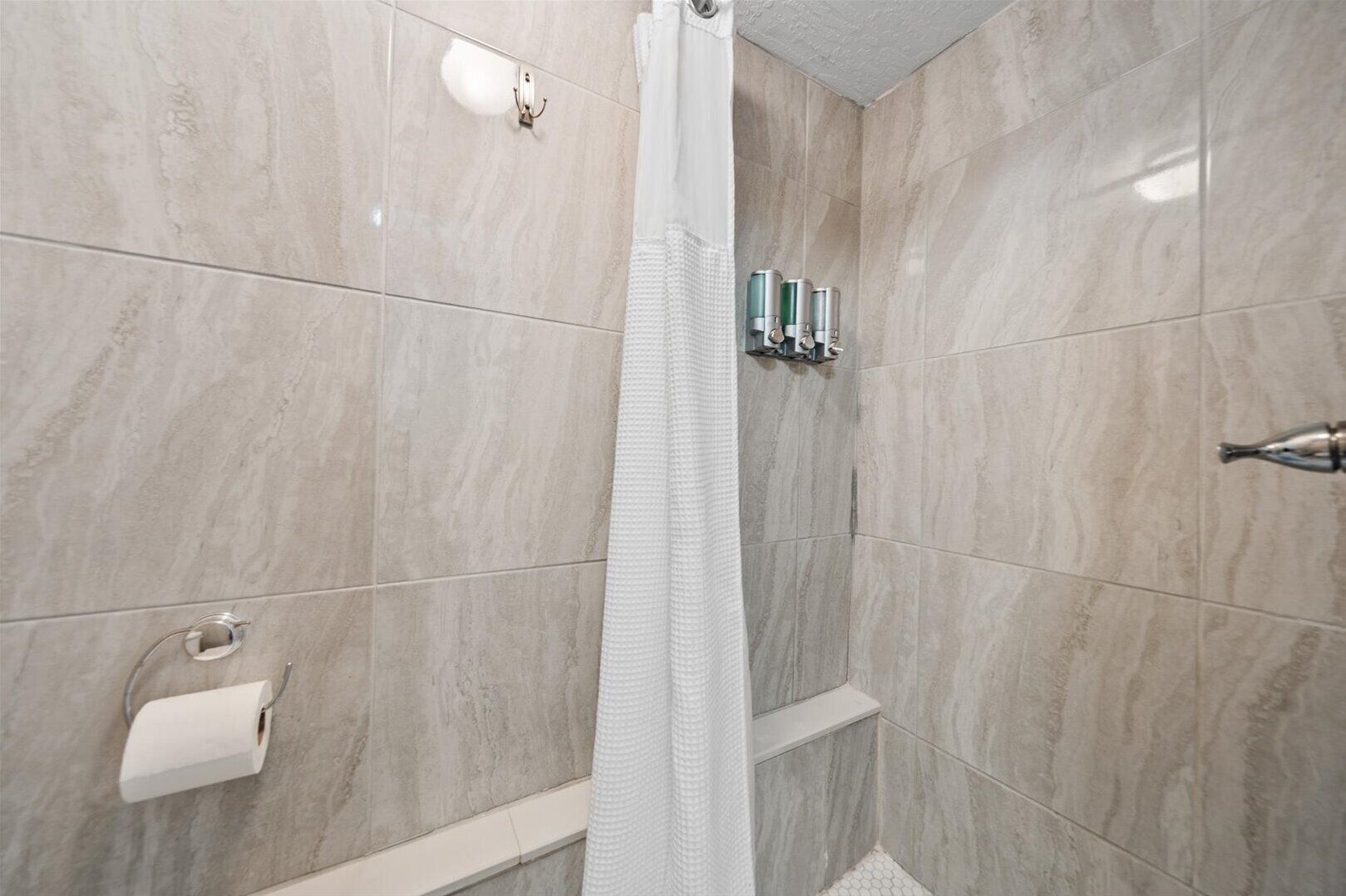 Une salle de bain moderne équipée d’une douche, de toilettes et d’un porte-serviettes.