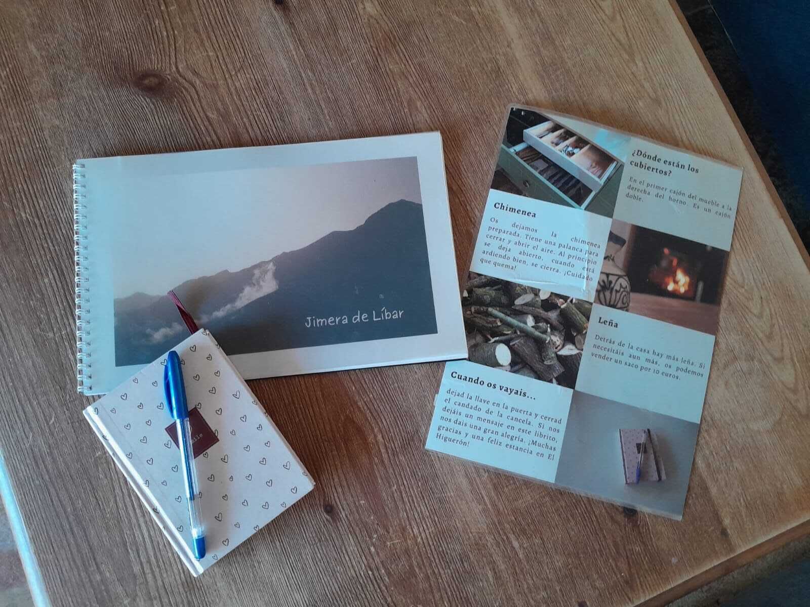 A notebook with a mountain landscape photo, a pen, and several cards with text and images on a wooden table.