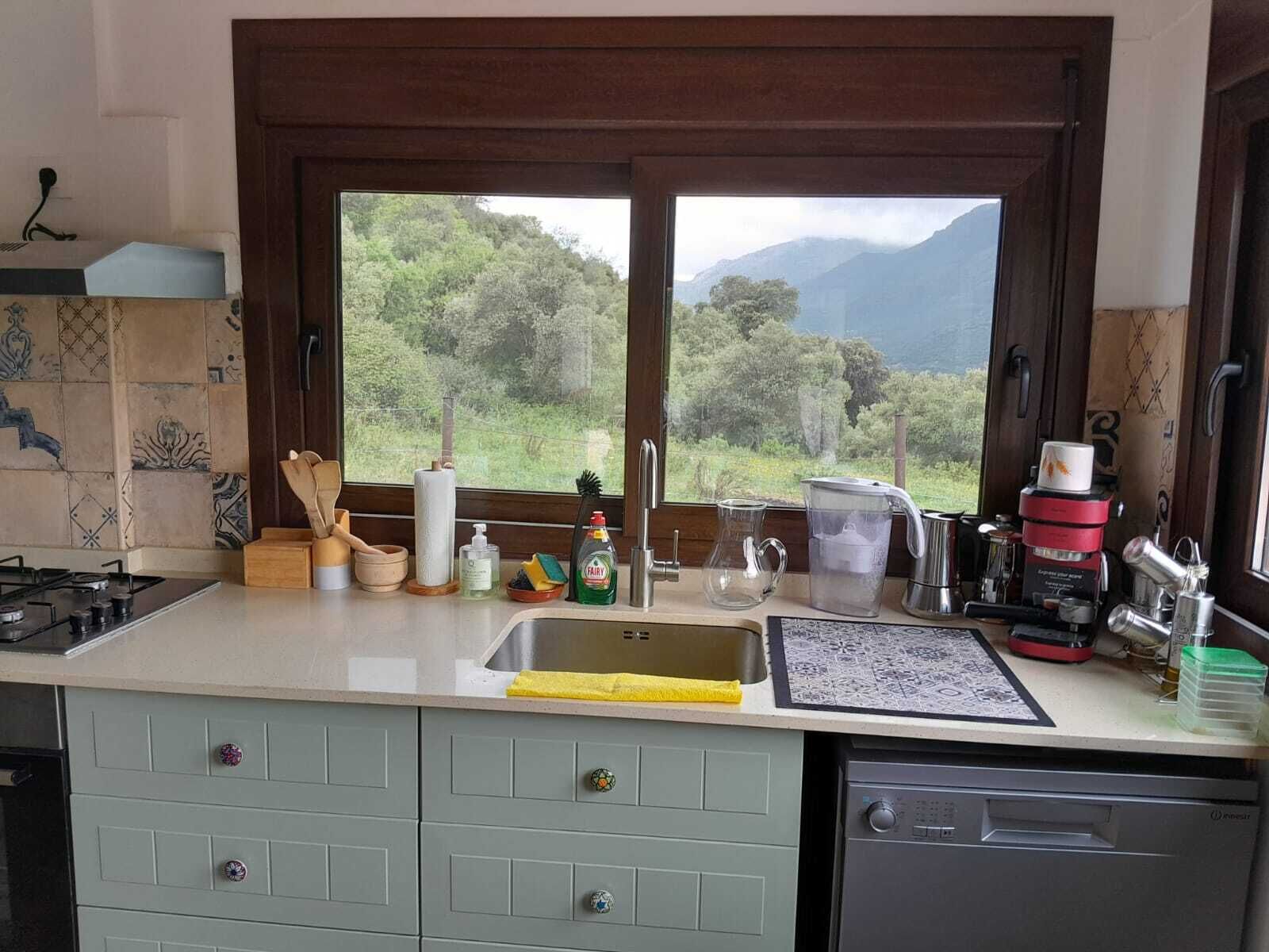 Une cuisine avec vue sur les montagnes, une cuisinière à gaz, un évier et divers ustensiles de cuisine.