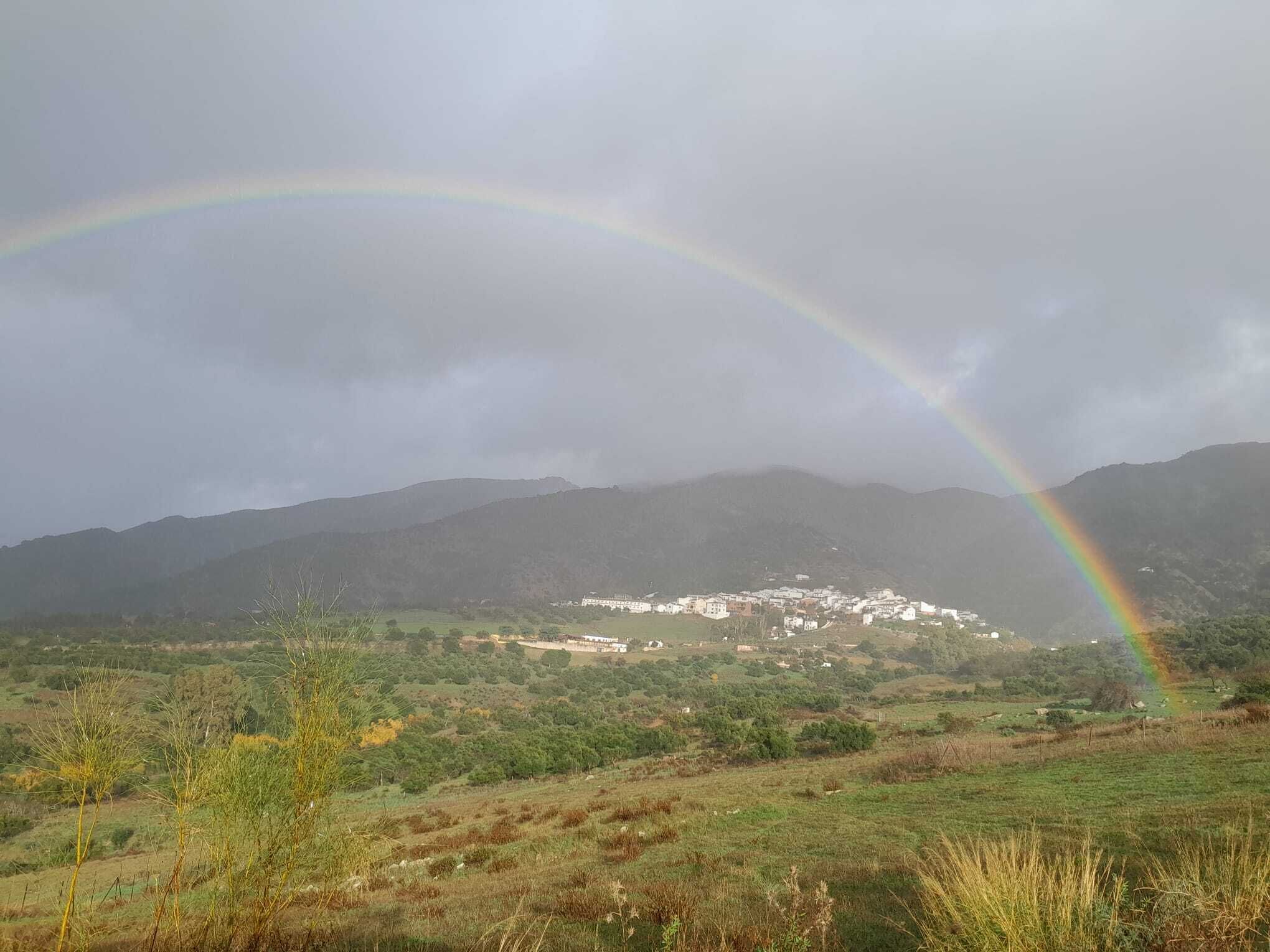 A rural landscape with a rainbow over a village.