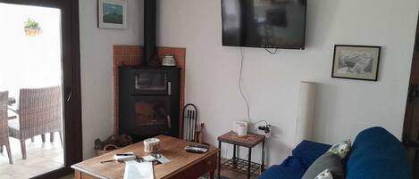 A living room with a fireplace, a television, a sofa, and a table with various items.