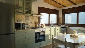 Una cocina con estufa, horno y pileta. Hay una ventana con vista al exterior.