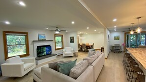 Amplia sala de estar con chimenea, un sofá grande y una zona de comedor con mesa y sillas.
