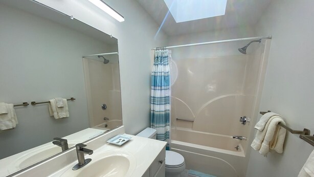 Een moderne badkamer met een grote spiegel, een wastafel, toilet en douchegedeelte.