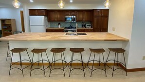Una cocina moderna con armarios de madera, una isla central con taburetes e iluminación colgante.