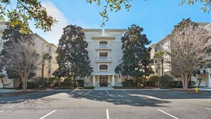 A multi-story hotel with a central entrance, surrounded by trees and a parking lot. - Pool Views, Minutes to Beach, Ground Floor Unit + Free Attraction Tickets! (Santa Rosa Beach)