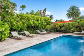 A pool area with lounge chairs and a clear blue pool.