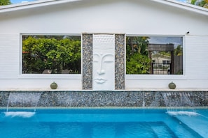 A modern building with a pool, a decorative face sculpture, and a tiled facade. - Delray Beach's Ultimate Retreat Asian-Inspired Oasis and Exclusive Private Patio (Delray Beach)