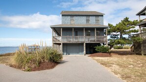 A two-story beachfront house with a covered porch and a garage.